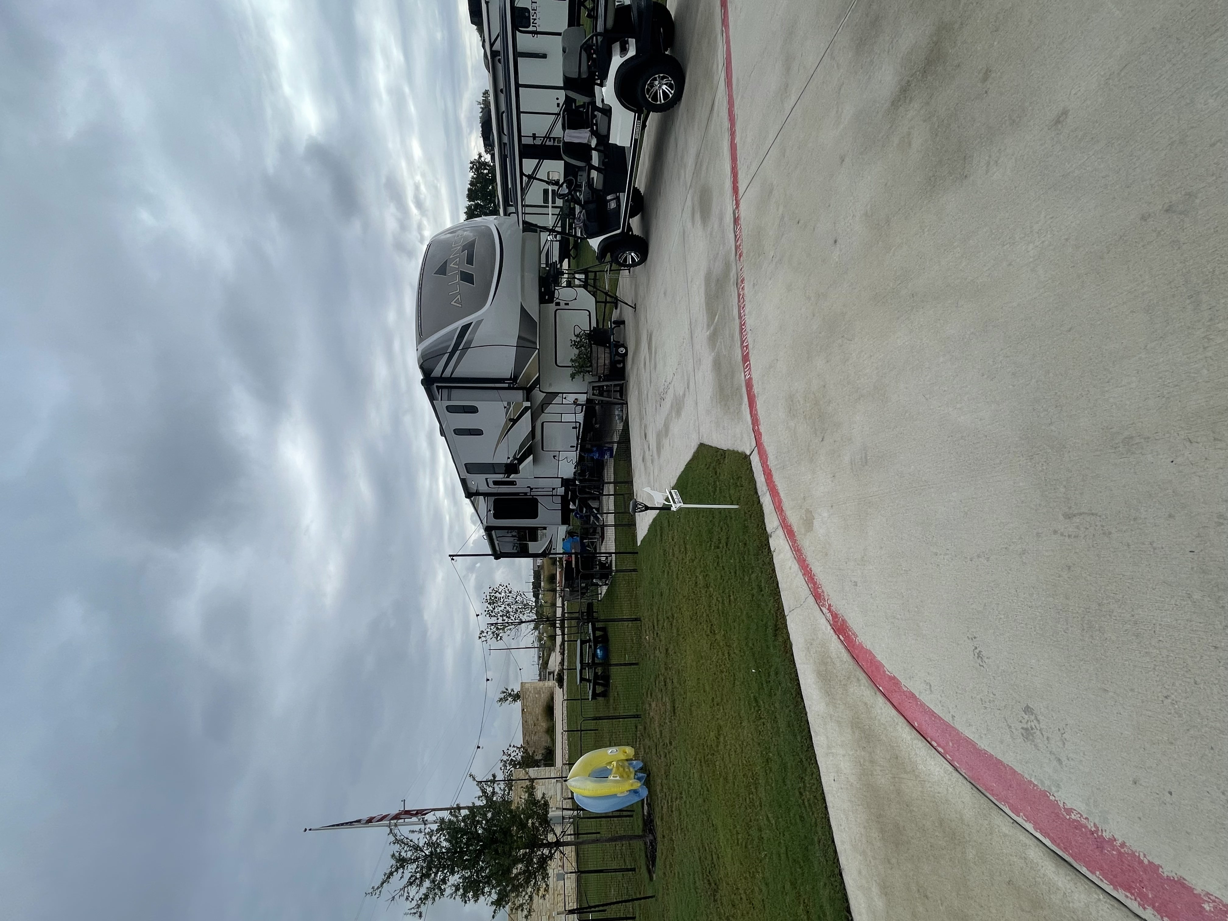 Alliance fifth wheel RV set up at a Central Texas RV resort with golf cart and outdoor living space