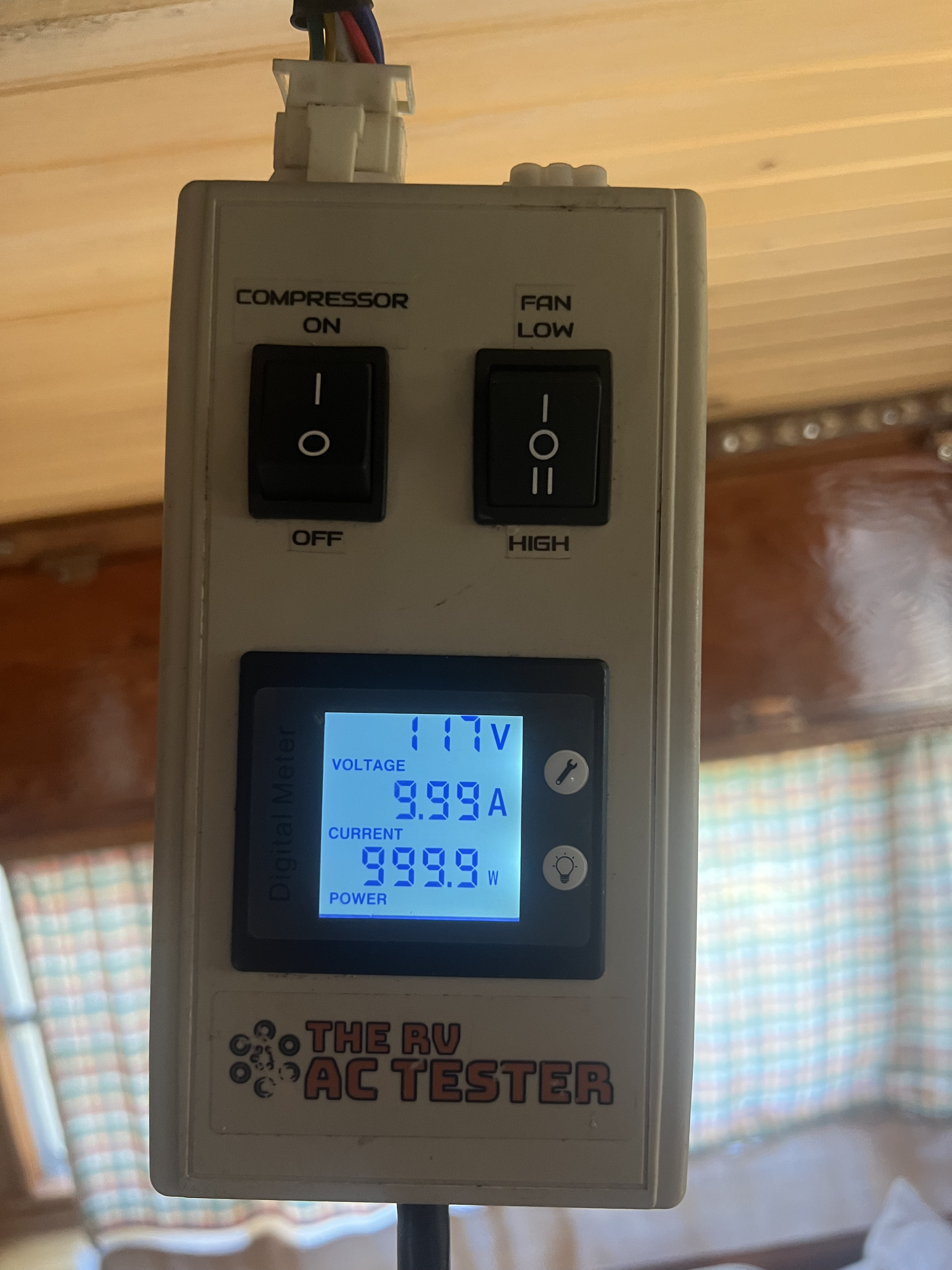 The RV AC Tester device showing 117V, 9.99A, and 999.9W with compressor on and fan on high — maximum compressor draw documented during an RV air conditioner service visit — Boss Bull Mobile RV Services