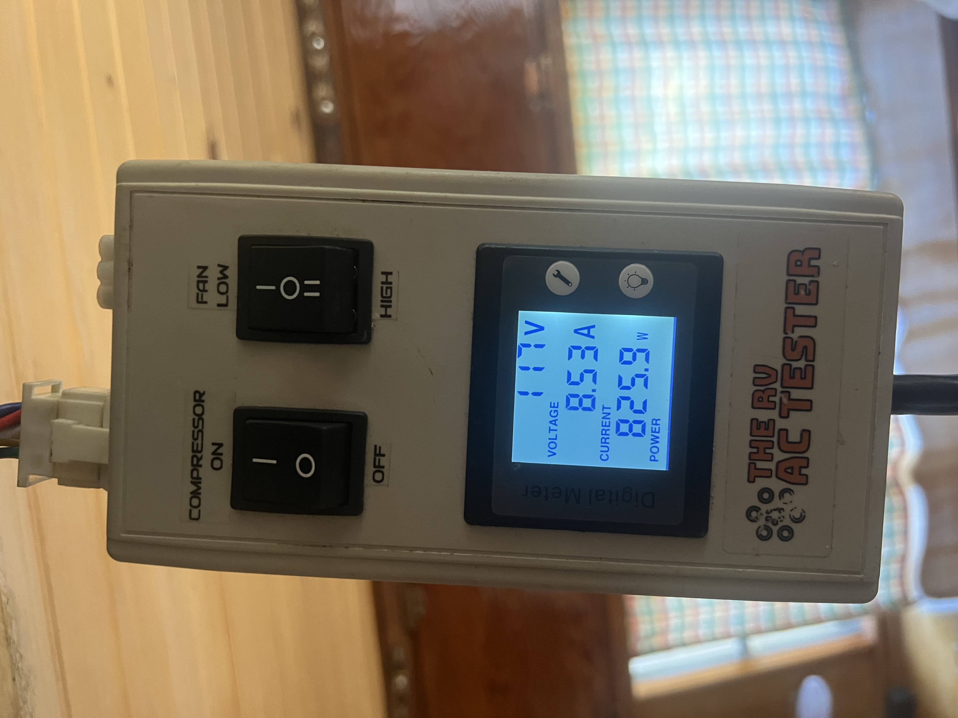 The RV AC Tester device showing 117V, 8.53A, and 825.9W with compressor on and fan on low during an in-field RV air conditioner service — Boss Bull Mobile RV Services