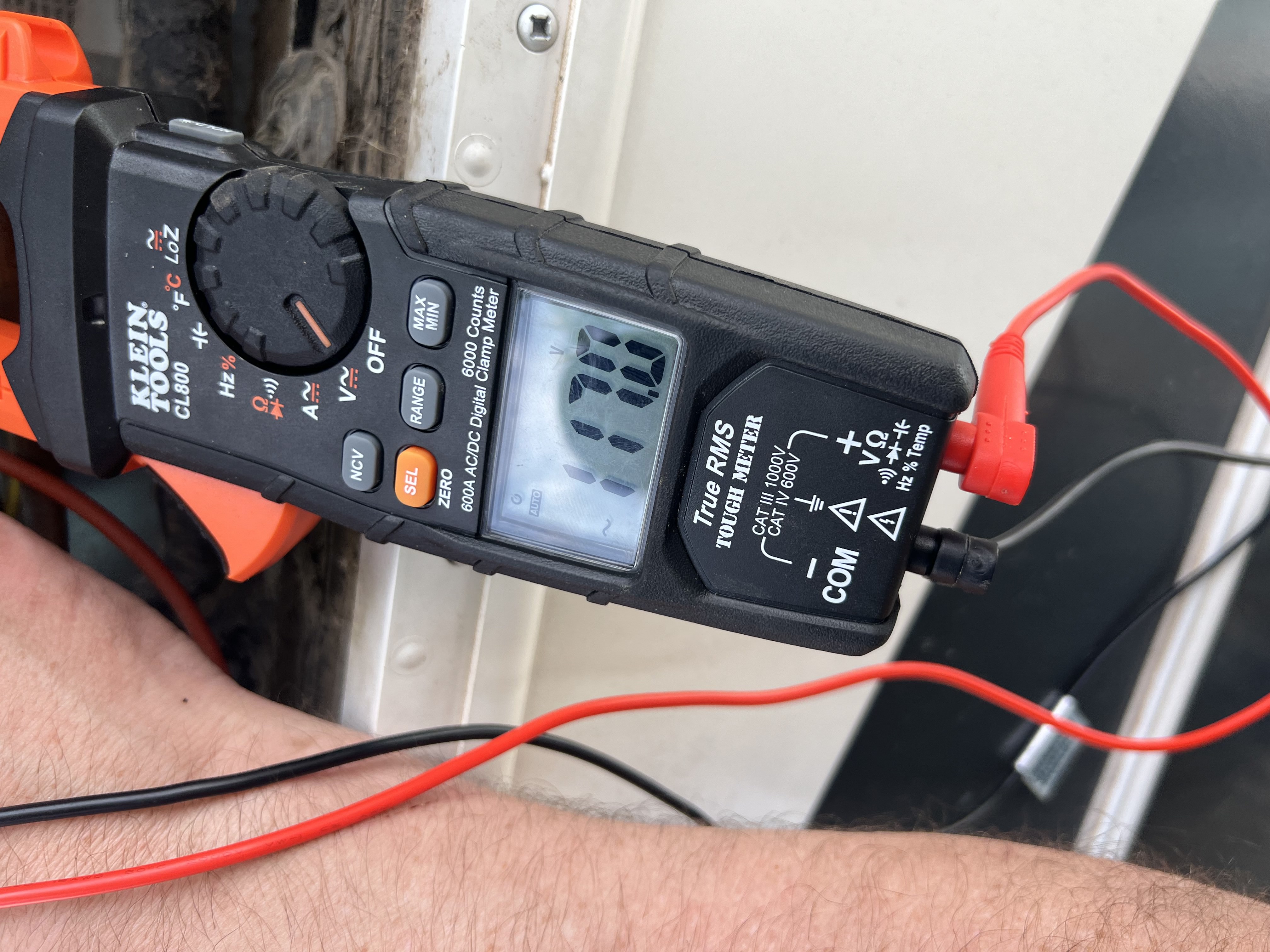 Technician using a voltage meter to test the electrical supply at an RV refrigerator during a no-cooling diagnostic service visit — Boss Bull Mobile RV Services