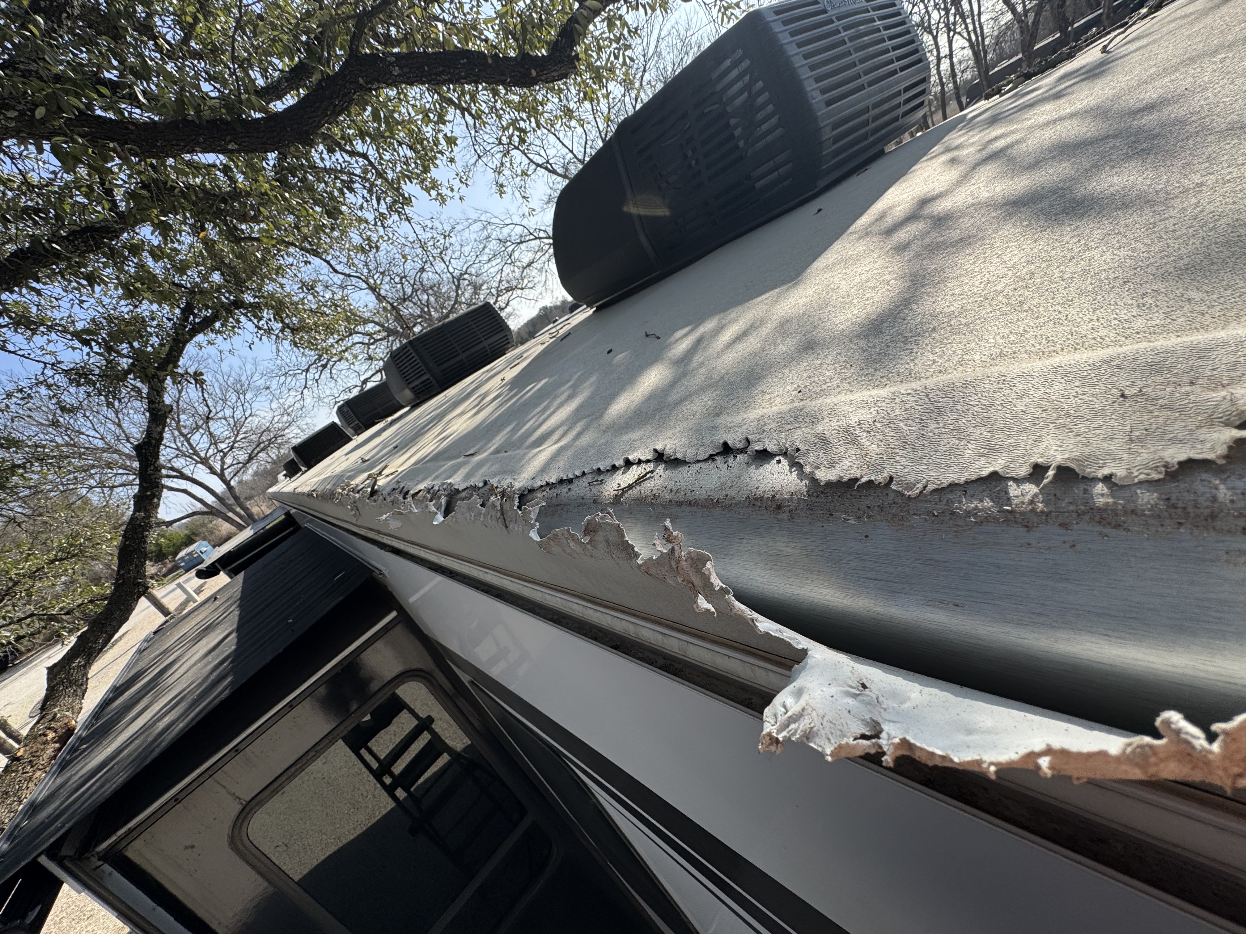 RV rubber roof membrane separating from the aluminum drip rail along the full length of the sidewall — active water intrusion path documented before repair — Boss Bull Mobile RV Services