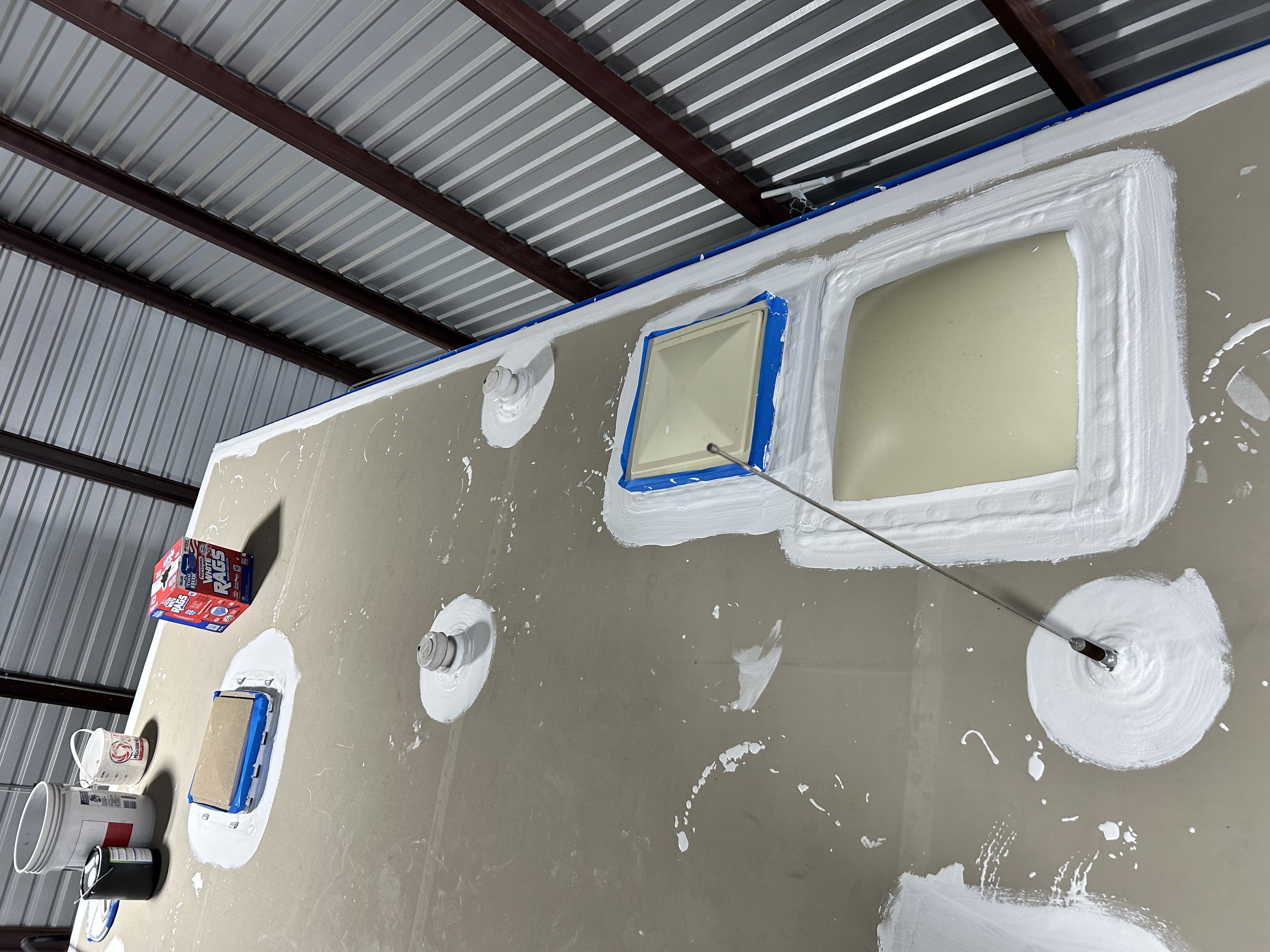 White lap sealant applied along the termination rail and around roof penetrations during an RV roof restoration — Boss Bull Mobile RV Services