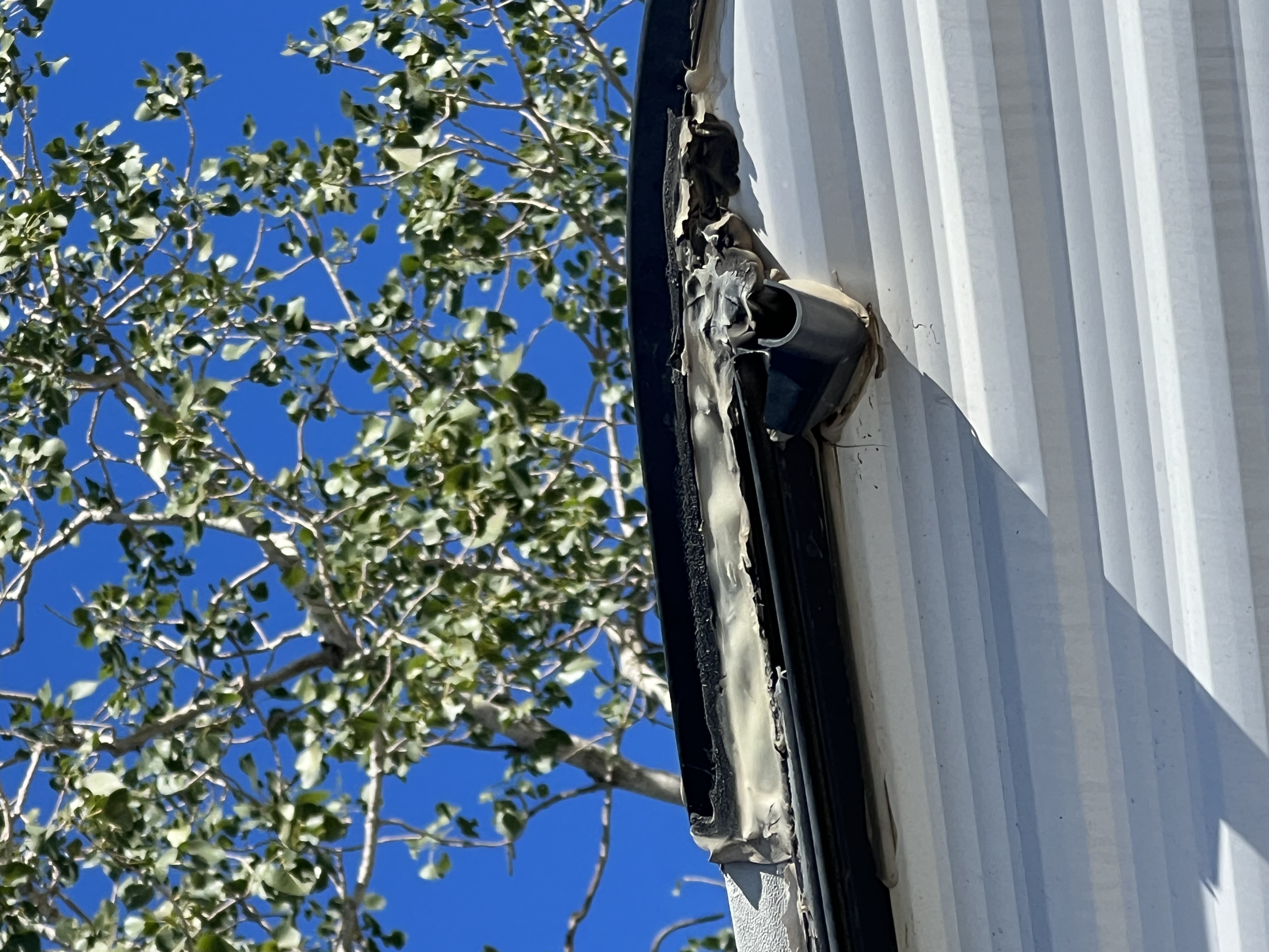 RV roof drip edge showing severely cracked, lifting, and peeling lap sealant along the termination rail — active failure requiring resealing — Boss Bull Mobile RV Services