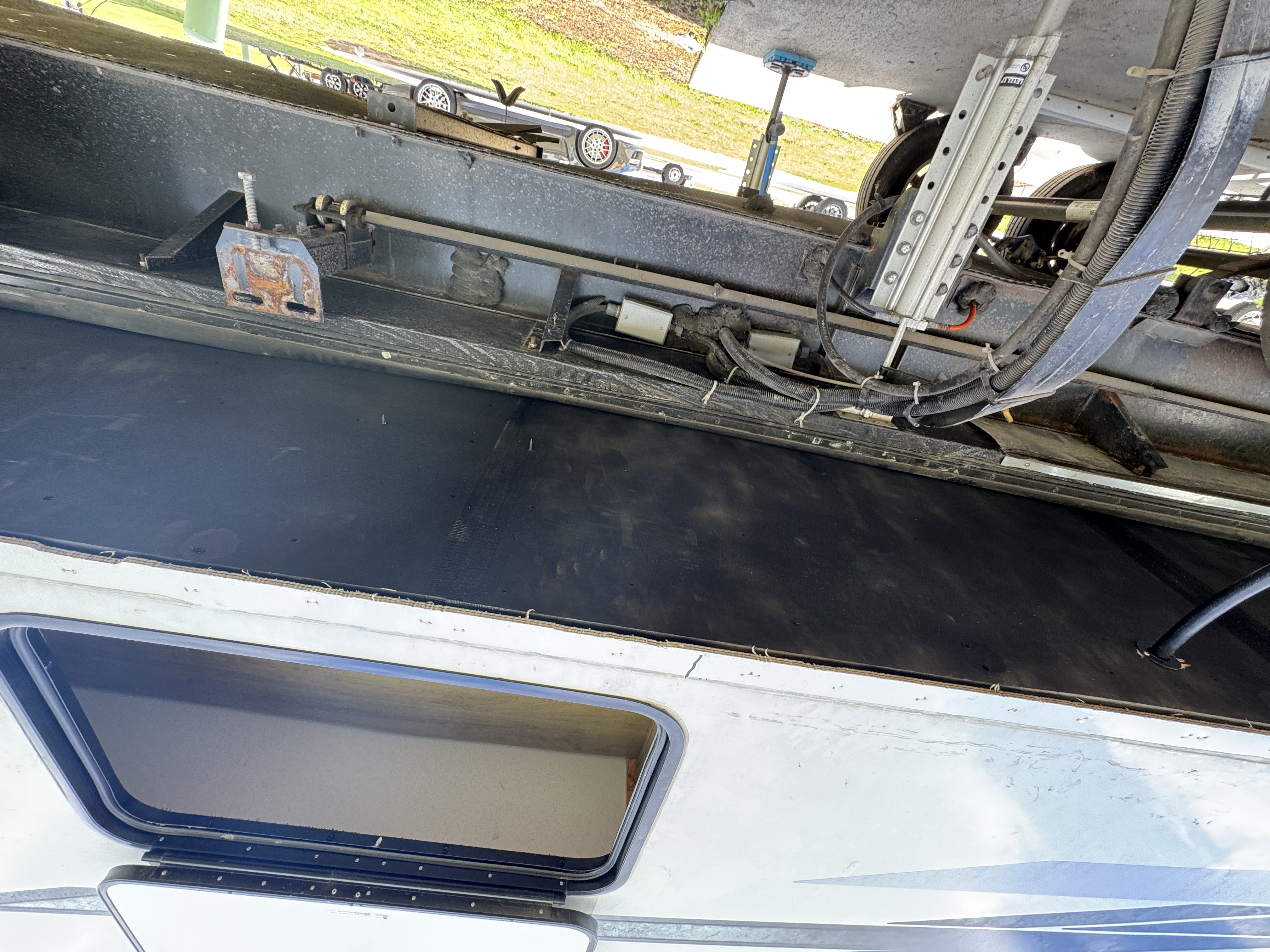 Underside view of an extended RV slide room with new black subfloor decking installed — slide floor replacement in progress — Boss Bull Mobile RV Services