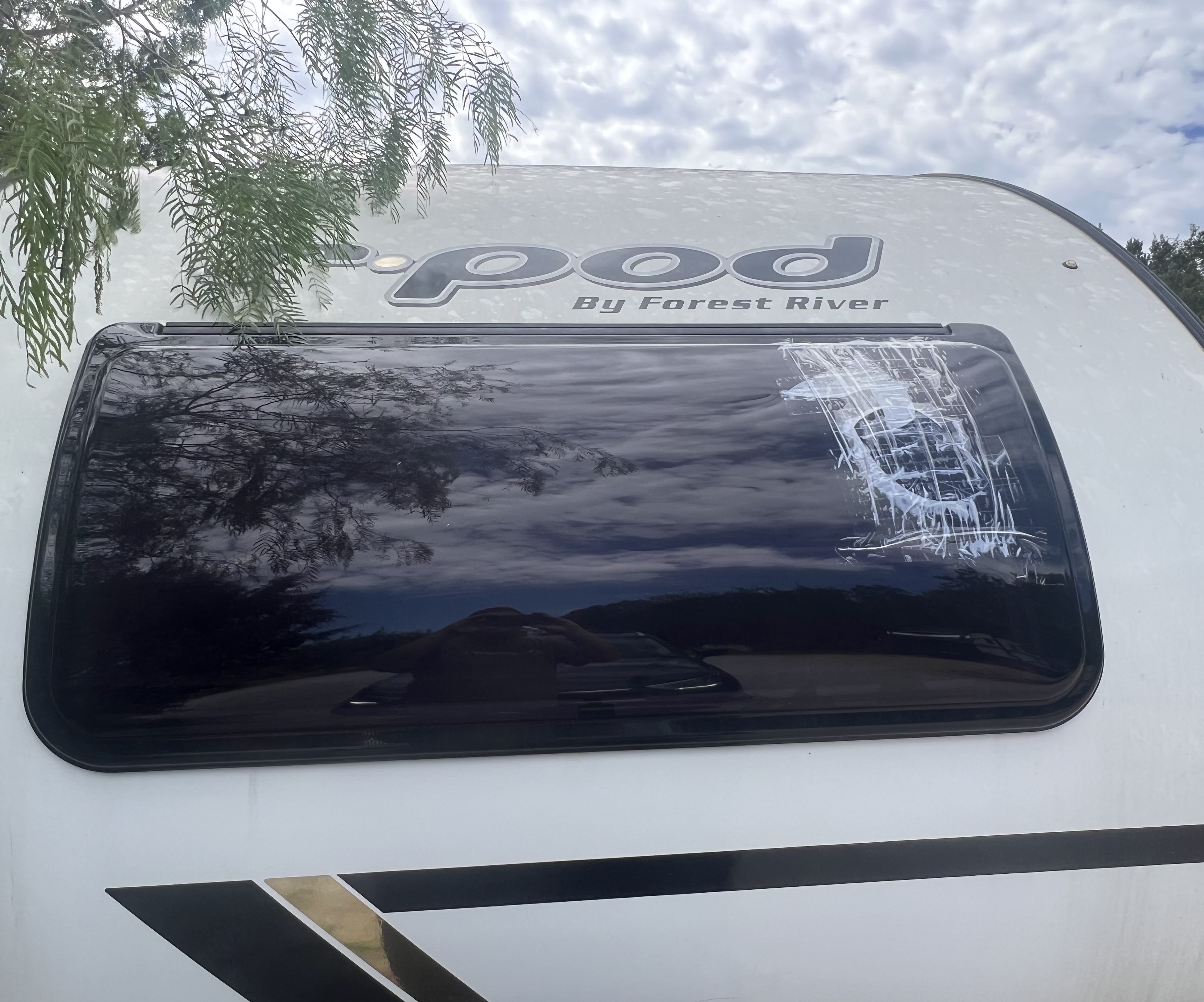 RV window showing impact damage — crack pattern radiating from a central impact point documenting the pre-repair condition — Boss Bull Mobile RV Services