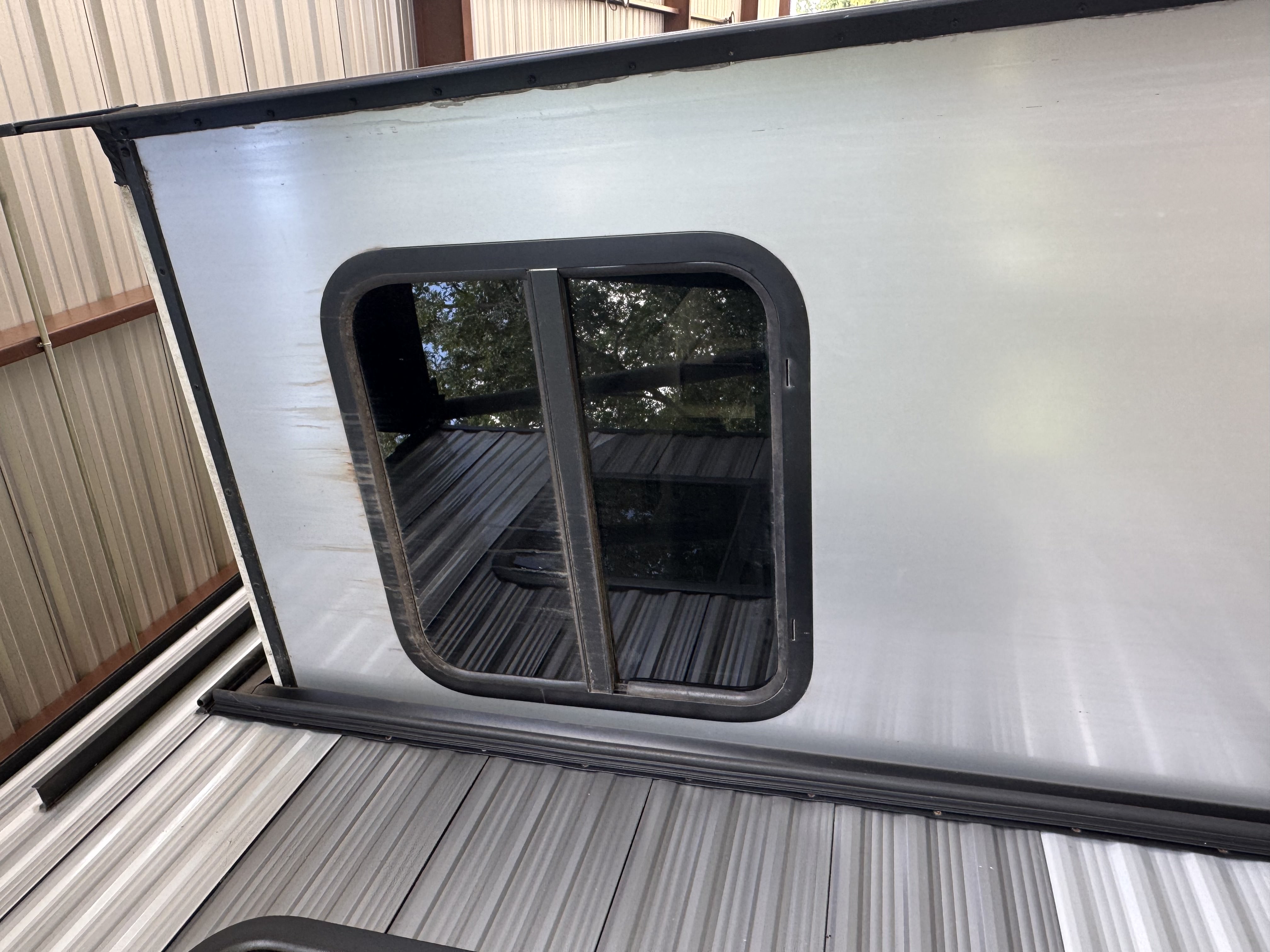RV slide room end cap panel removed — window frame and framing members exposed with rust staining running from the window seal area confirming long-term water intrusion into the slide structure — Boss Bull Mobile RV Services